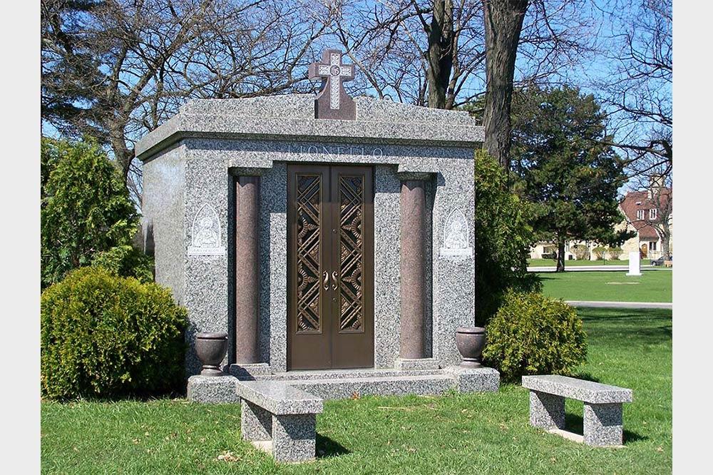 Front view of private mausoleum with two front benches surrounded by bushes