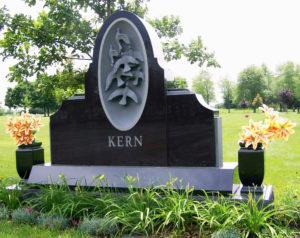 Black upright monument with vases and carved doves